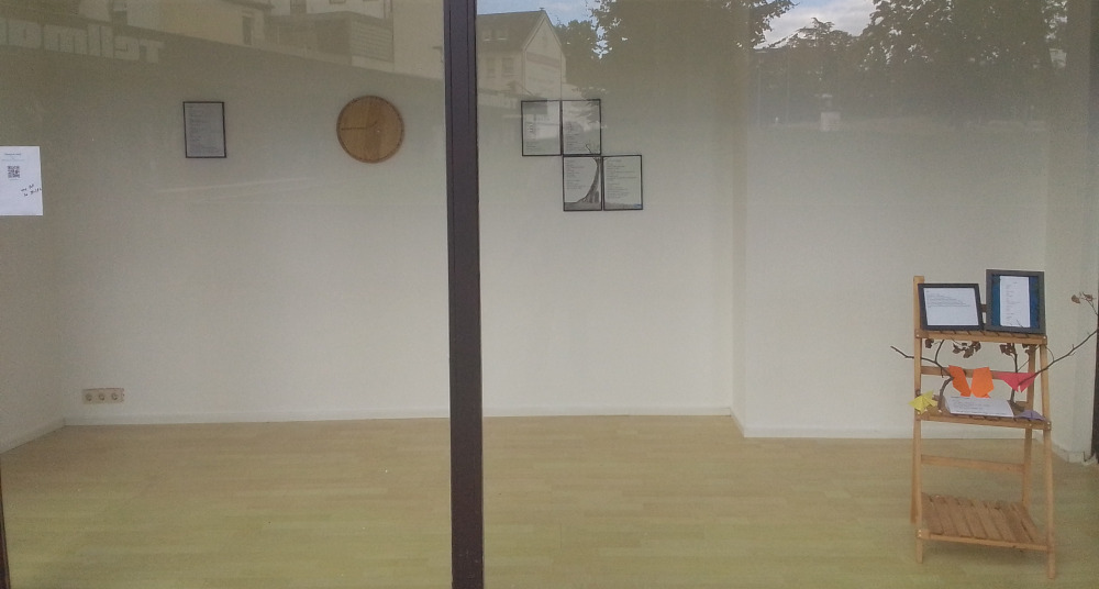 Schaufenster, in dem einige gerahmte Gedichte hängen oder auf einem kleinen Holzregal aufgestellt sind